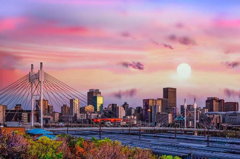 Skyline of Johannesburg and Vaal River with full moon rising over city shortly after sunset